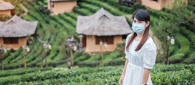 Glückliche Touristenfrau, die chirurgische Gesichtsmaske trägt, genießen schönen Teegarten