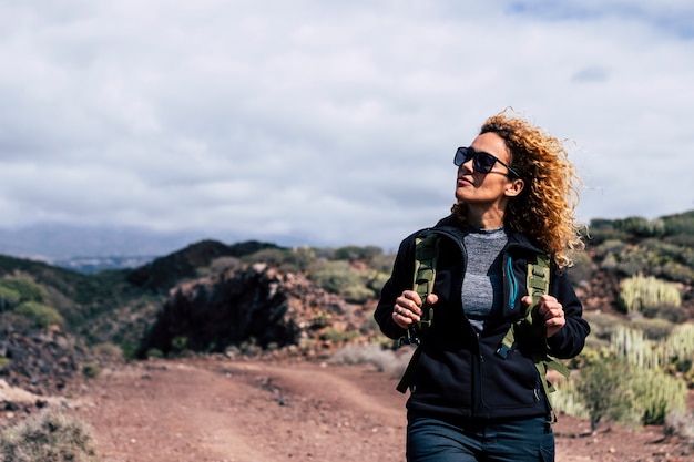 Glückliche unabhängige schöne erwachsene kaukasische Frau beim Trekking im Freien, die die Natur genießt