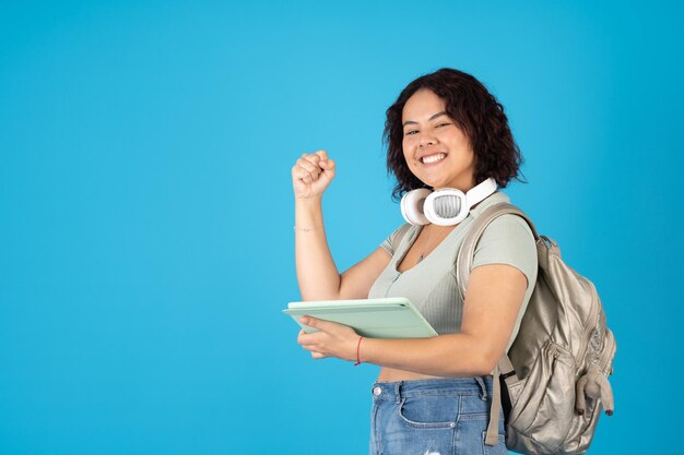 Glückliche und ermächtigte College-Frau mit einem Rucksack, der ein digitales Tablet verwendet