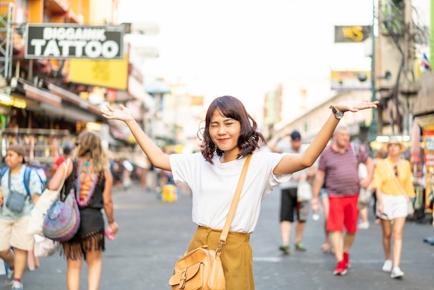 Glückliche und schöne asiatische Frau, die an Khao Sarn Road, Thailand reist