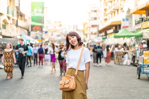 Glückliche und schöne asiatische Frau, die an Khao Sarn Road, Thailand reist