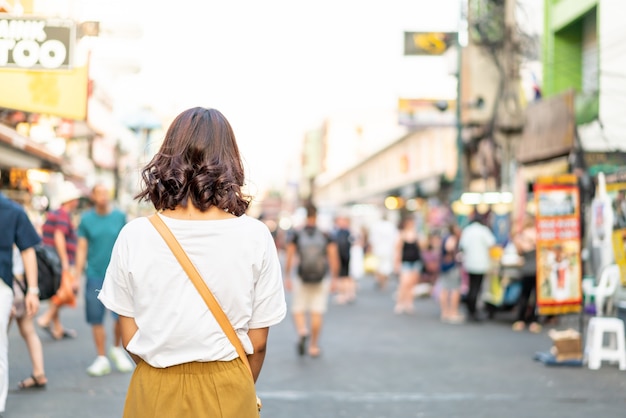 Glückliche und schöne asiatische Frau, die an Khao Sarn Road, Thailand reist