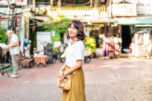 Glückliche und schöne asiatische Frau, die an Khao Sarn Road, Thailand reist