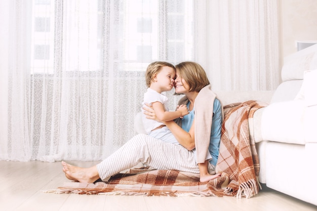 Glückliche und schöne Mutter-Kind-Familie zusammen zu Hause im Wohnzimmer