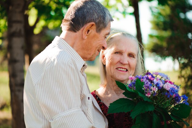 Glückliche und sehr alte Paare, die in einem Park an einem sonnigen Tag lächeln.