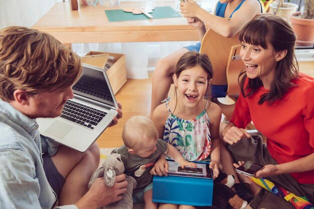 Foto glückliche verspielte familie, die digitale geräte im kinderzimmer nutzt