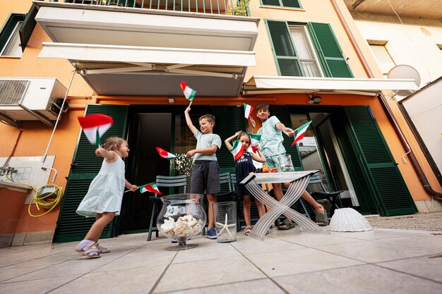 Glückliche vier Kinder mit italienischen Flaggen, die den Tag der Republik Italien feiern