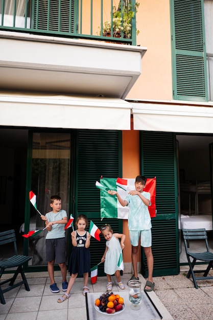 Glückliche vier Kinder mit italienischen Flaggen, die den Tag der Republik Italien feiern