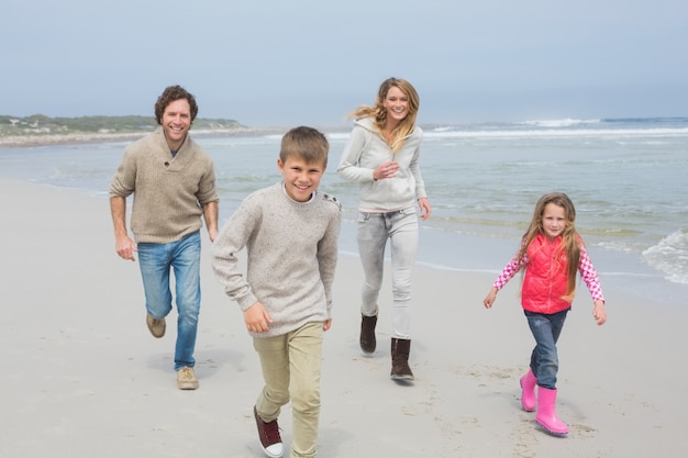 Glückliche vierköpfige Familie, die am Strand läuft