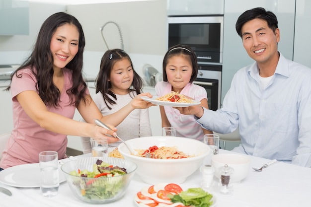 Glückliche vierköpfige Familie, die Spaghettimittagessen in ihm Küche genießt