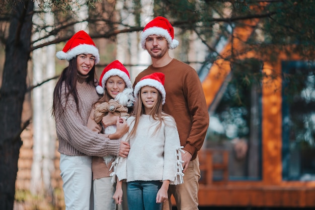 Glückliche vierköpfige Familie, die Weihnachtsferien genießt. Eltern mit Kindern in der roten Weihnachtsmütze