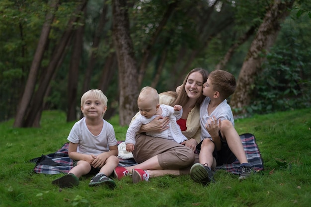 Glückliche vierköpfige Familie mit Picknick auf der Wiese Mutter und drei Kinder sitzen auf der Picknickdecke