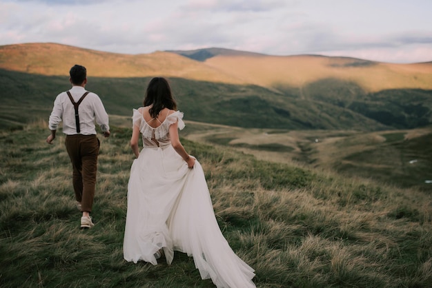 Glückliche wunderschöne Braut und Bräutigam zu Fuß Händchen haltend Boho-Stil Hochzeitspaar wunderschönes Paar