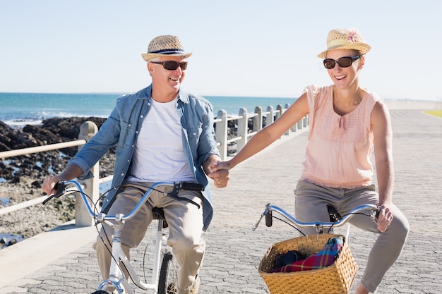 Foto glückliche zufällige paare, die eine fahrradfahrt auf den pier anstreben