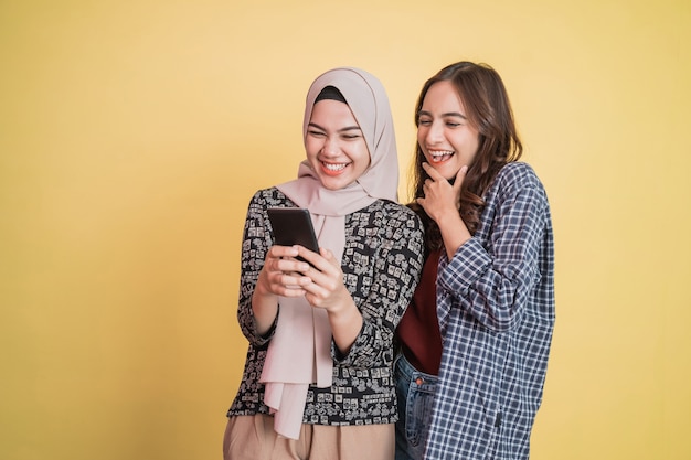 Glückliche zwei asiatische Frauen benutzen ein Handy und sind überrascht, wenn sie den Telefonbildschirm sehen