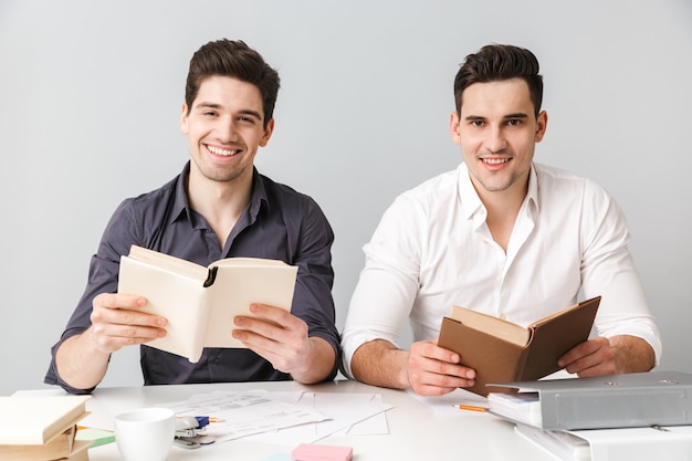 Glückliche zwei junge Geschäftsleute, die Bücher lesen.