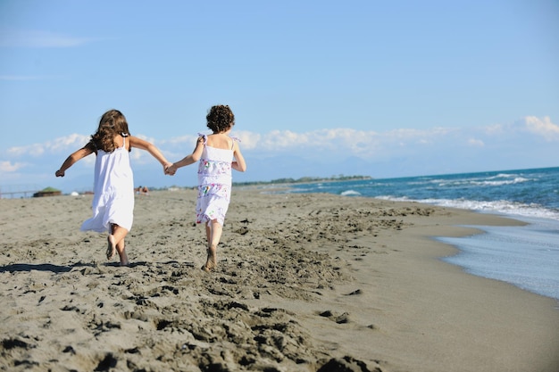 Glückliche zwei kleine Mädchen haben Spaß und Freude am schönen Strand, während sie vor Freude davonlaufen