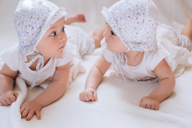 Glückliche Zwillinge in lustigen Hüten. Kinder Mädchen 7 Monate.