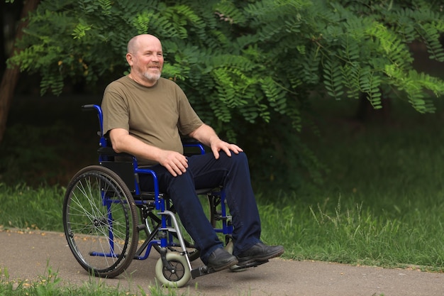 Glücklicher älterer behinderter Mann, der im Rollstuhl draußen sitzt