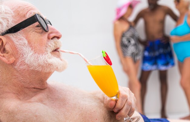 Glücklicher älterer Mann mit Party im Schwimmbad