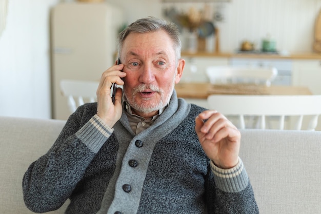 Glücklicher älterer Mann mittleren Alters, der auf dem Smartphone mit Freunden der Familie, seinem älteren, reifen Großvater, spricht