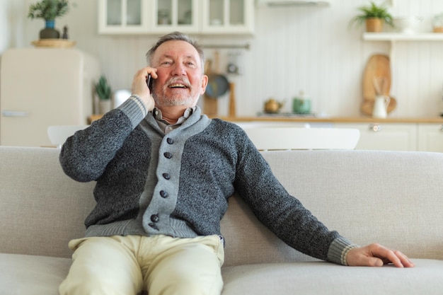 Glücklicher älterer Mann mittleren Alters, der auf dem Smartphone mit Freunden der Familie, seinem älteren, reifen Großvater, spricht
