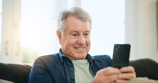 Glücklicher älterer Mann Telefon und entspannen Sie sich auf dem Sofa für Kommunikation gute Nachrichten oder Netzwerk zu Hause Reife männliche Person Lächeln auf mobilem Smartphone für Online-Chat Text oder Suche auf der Couch zu Hause