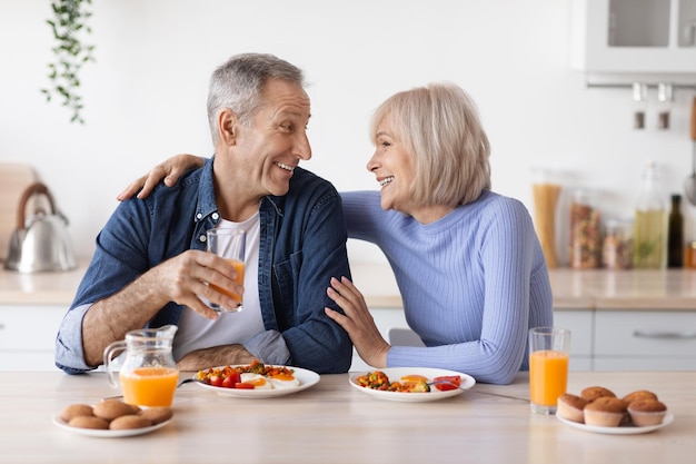 Glücklicher älterer Mann und Frau, die zu Hause zu Mittag essen