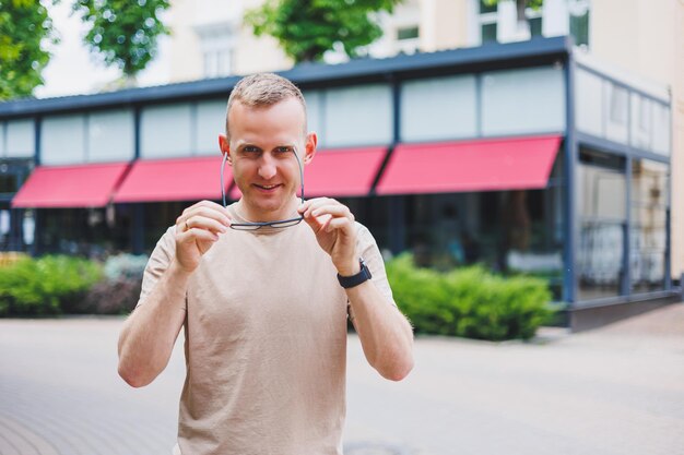 Glücklicher afrikanischer Gelegenheitsmann mit Brille sitzt am Cafétisch und blickt in die Kamera. Fröhlicher schwarzer Student posiert mit Buch im Kaffeehaus. Lächelnder Geschäftsmann arbeitet am Laptop im Cafeteria-Porträt