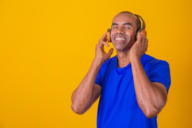 Glücklicher afrikanischer Mann lächelt und hört Musik über Kopfhörer