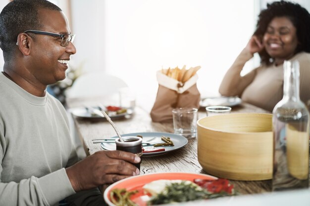 Glücklicher afrikanischer Vater, der Yerba Kumpel während des Mittagessens zu Hause trinkt