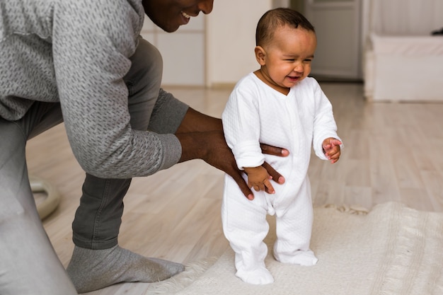 Glücklicher Afroamerikaner-Vater, der lächelndes Baby hält.