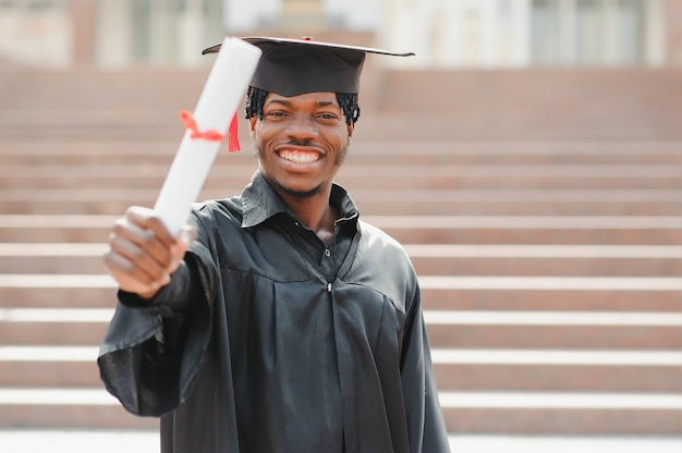 Glücklicher afroamerikanischer männlicher Hochschulabsolvent bei der Zeremonie