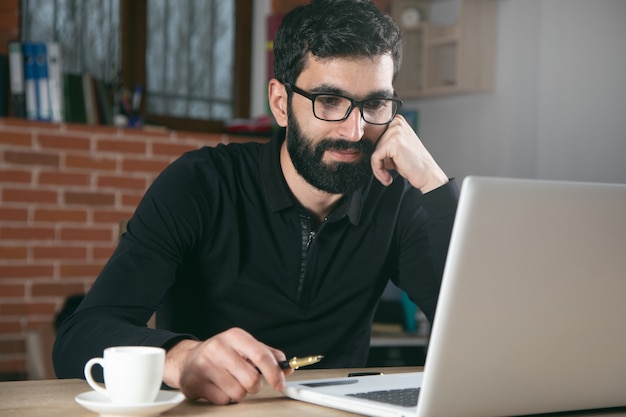 Glücklicher arbeitender Mann im Bürotisch