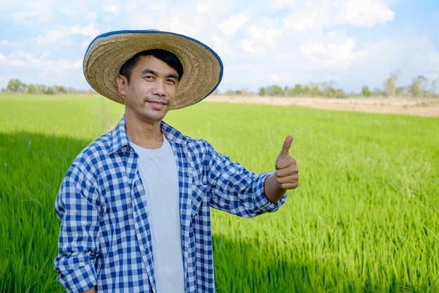 Glücklicher asiatischer männlicher Bauer im Reisfeld
