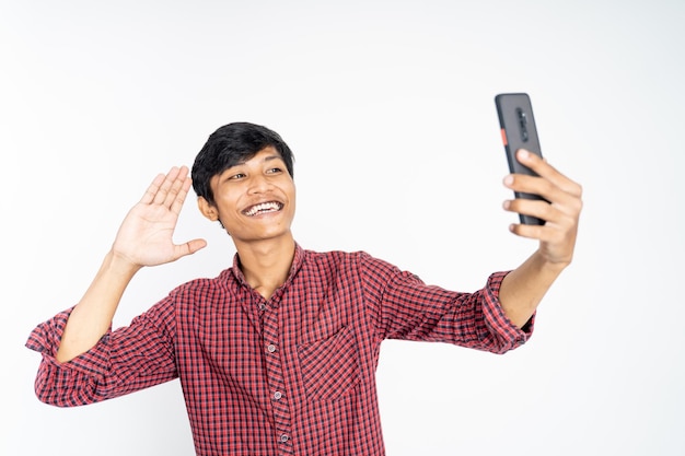 Glücklicher asiatischer Mann, der ein Selfie mit der Telefonkamera auf isoliertem Hintergrund macht