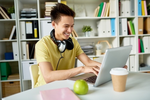 Glücklicher asiatischer Student mit Laptop