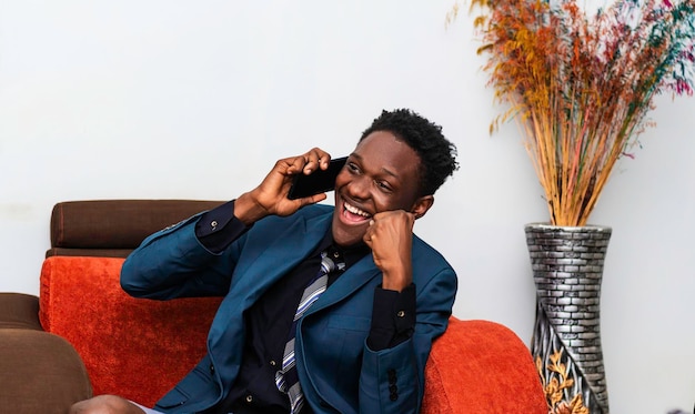 Glücklicher aufgeregter junger schwarzer Geschäftsmann, der am Handy spricht