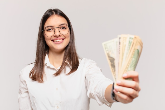 Glücklicher Ausdruck der jungen hübschen Frau und Halten von Dollarbanknoten