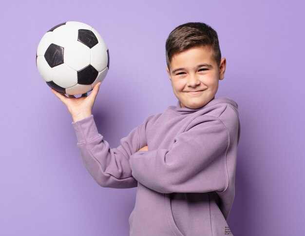 Glücklicher Ausdruck des kleinen Jungen und hält einen Fußball