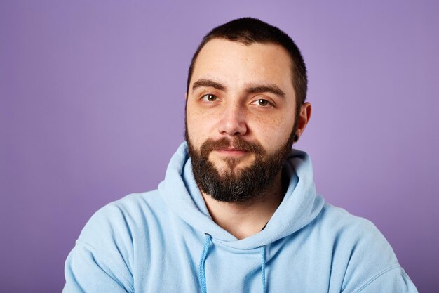 Glücklicher bärtiger Mann trägt blauen Pullover auf violettem Hintergrund freundliches Lächeln Kopierbereich