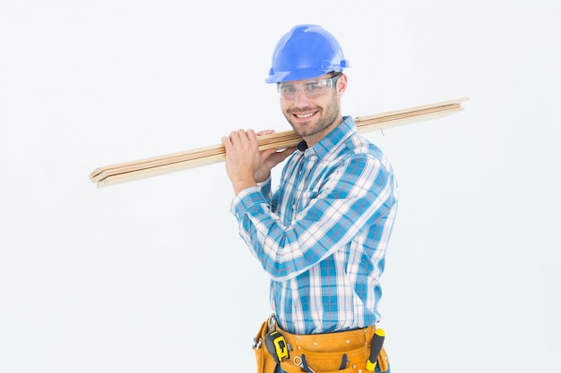 Glücklicher Bauarbeiter, der hölzerne Planken trägt