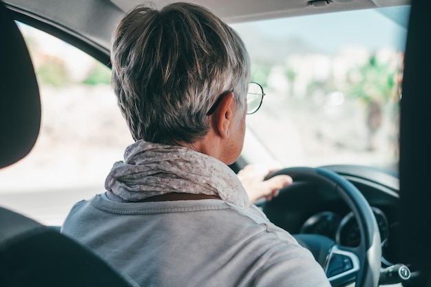 Glücklicher Besitzer Hübsche, reife Frau sitzt entspannt in seinem neu gekauften Auto und schaut auf die Straße, die freudig lächelt Ein alter Senior fährt und hat funxA