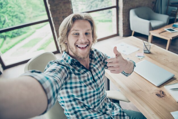 glücklicher blonder Kerl, der im Büro aufwirft