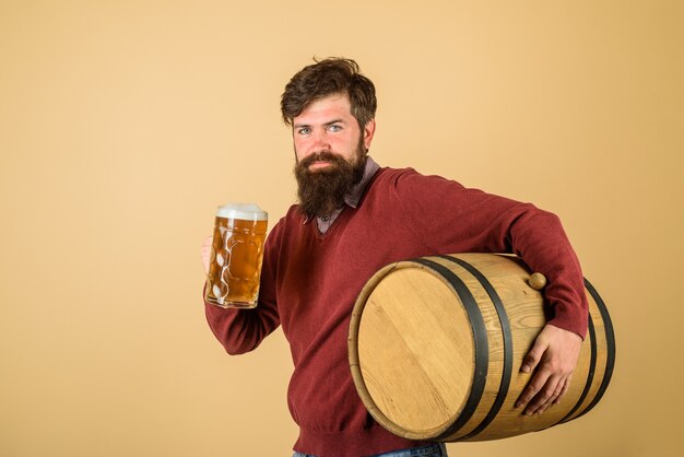 Glücklicher Brauer bärtiger Brauer hält Glas mit Bierprobe frisch gebrautes Bier Brauer hält Fass mit