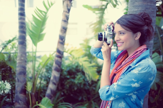 Glücklicher Brunette, der draußen ein Foto an einem sonnigen Tag macht