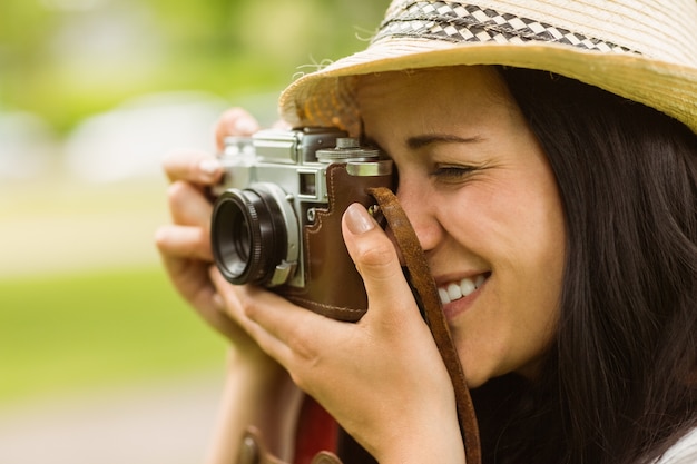 Glücklicher Brunette, der Foto mit Retro- Kamera macht