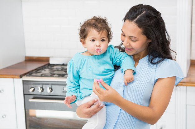 Glücklicher Brunette, der ihr Baby in der Küche einzieht