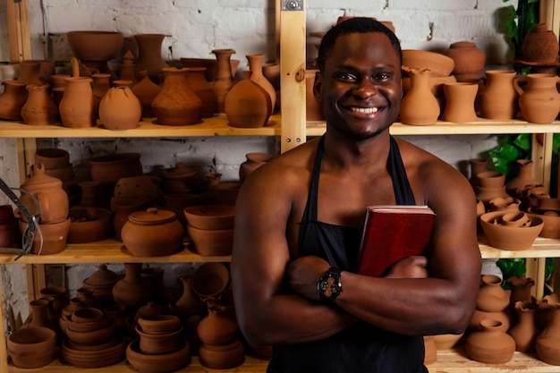 Glücklicher dunkelhäutiger afroamerikanischer Geschäftsmann Potter-Mann-Formteil in der Werkstatt. Bildhauer töpfert Tontopf in einem Atelierarbeitsplatz. Kreativität und Inspiration des Künstlers.