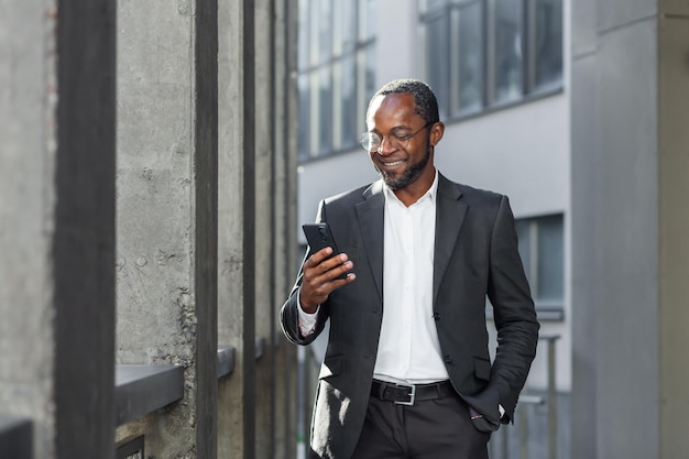 Glücklicher erfolgreicher afrikanisch-amerikanischer Geschäftsmann-Chef, der außerhalb der Bürogebäude-Manager-Holding geht